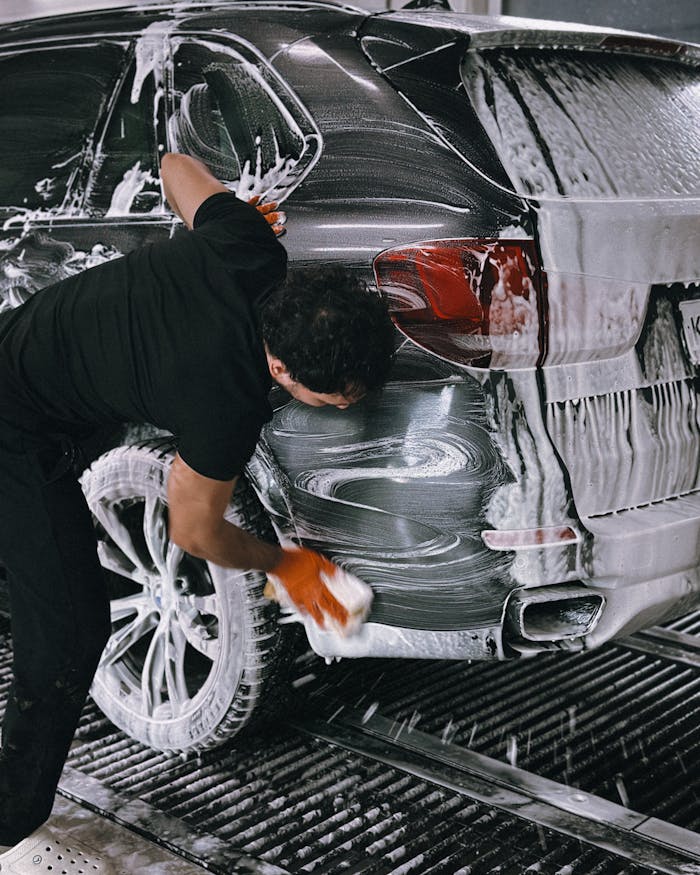 get-in-touch A person meticulously washing a car at a car wash using soap and a sponge.